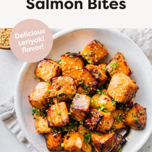 Air Fryer Salmon Bites in a serving bowl. Side bowl of spicy mayo and sesame seeds are next to the bowl of Air Fryer Salmon Bites.