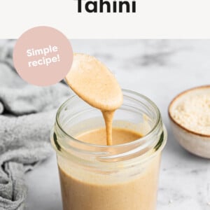 Spoon dripping tahini from a jar.