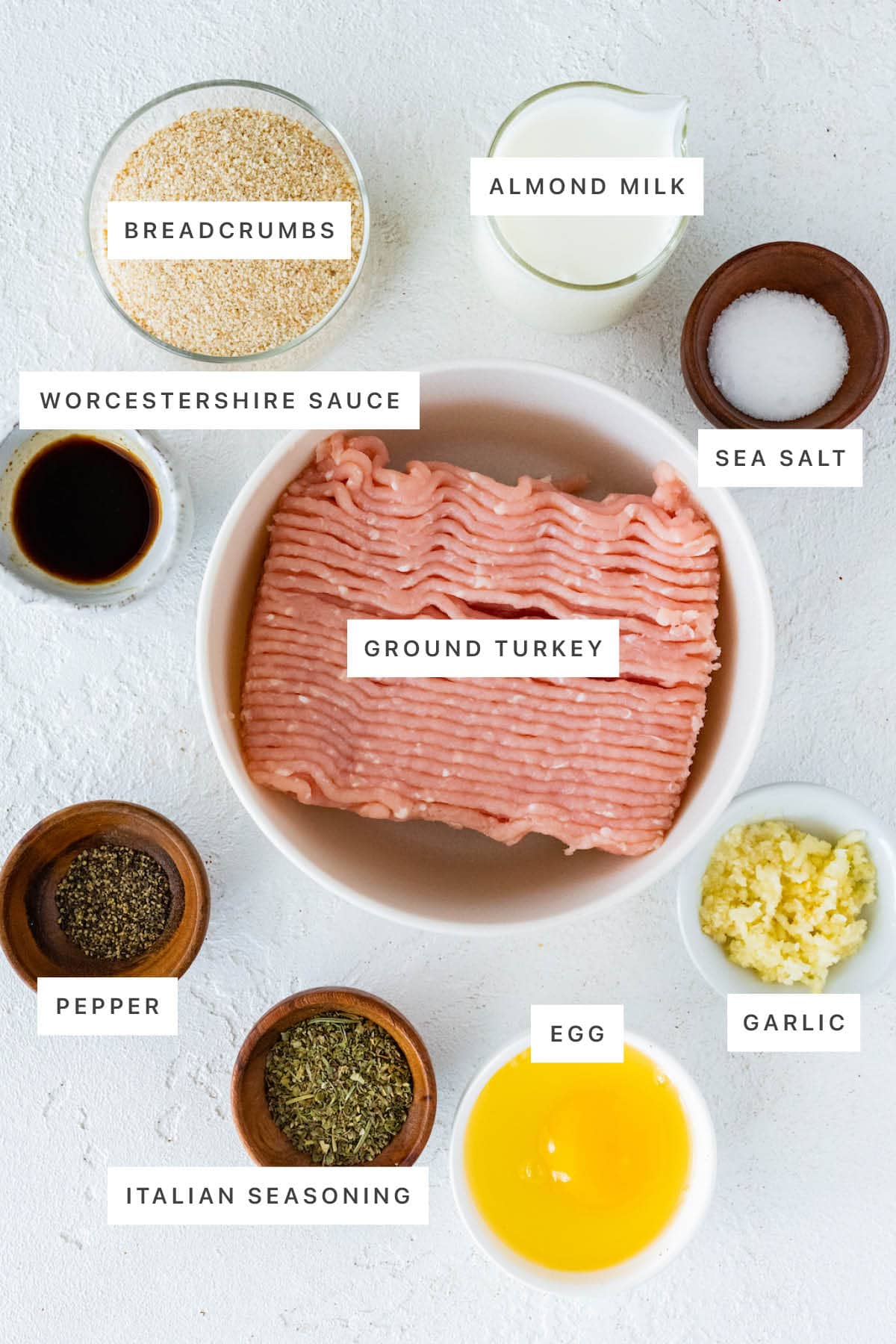 Ingredients measured out to make Baked Turkey Meatballs: breadcrumbs, almond milk, Worcestershire sauce, sea salt, ground turkey, pepper, Italian seasoning, egg and garlic.