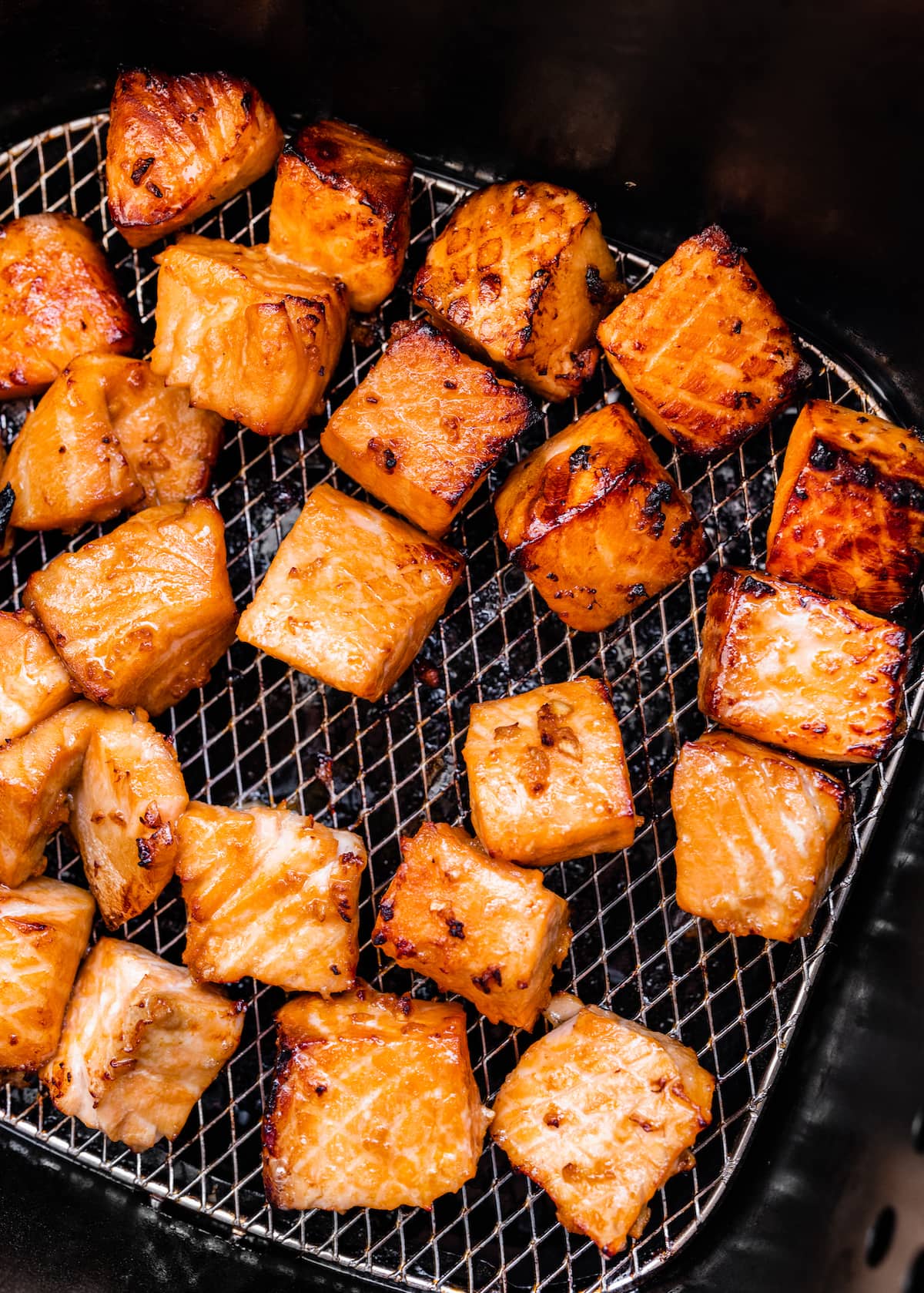 Salmon bites after being air fried on a wire rack in an air fryer.