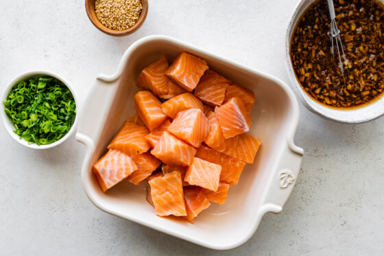 Raw cubed salmon bites in a small baking dish.
