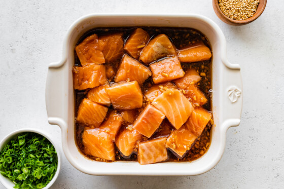 Raw salmon bites marinating in a small baking dish.