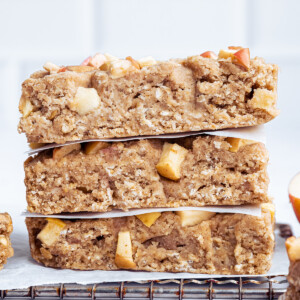 Three apple oatmeal bars stacked on one another on a cooling rack.