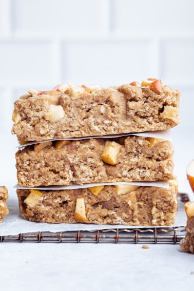 Three apple oatmeal bars stacked on one another on a cooling rack.