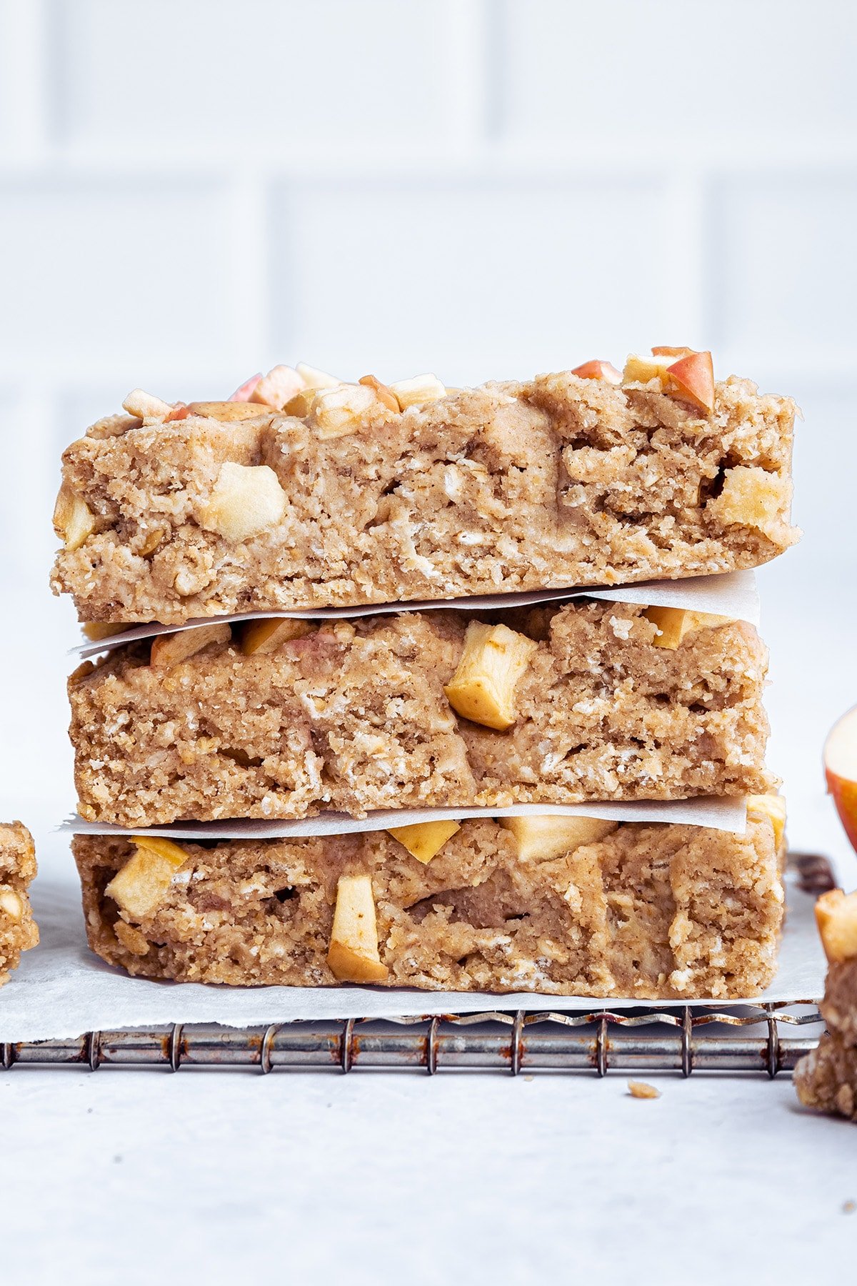 Three apple oatmeal bars stacked on one another on a cooling rack.