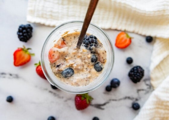 Cottage cheese overnight oats in a mason jar with fresh berries and a metal spoon.