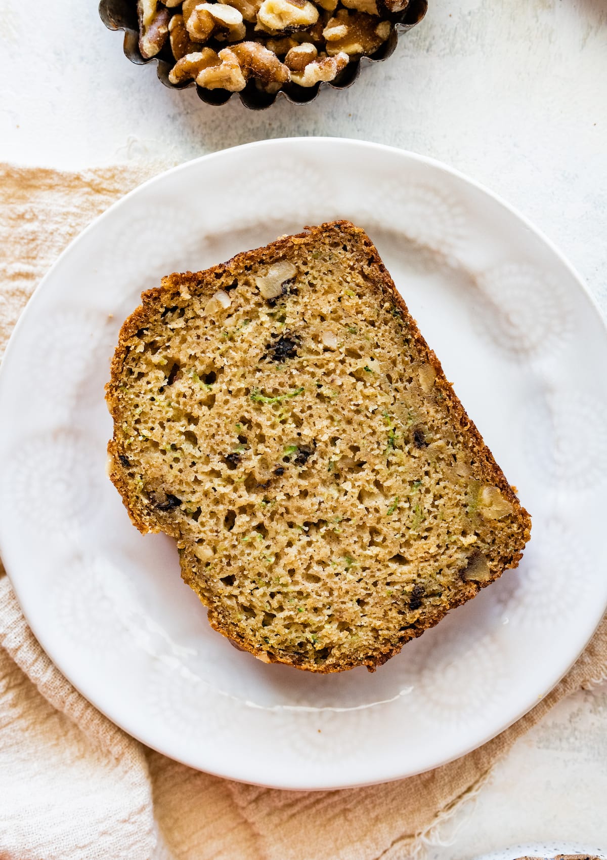 A slice of healthy zucchini bread on a small white plate.