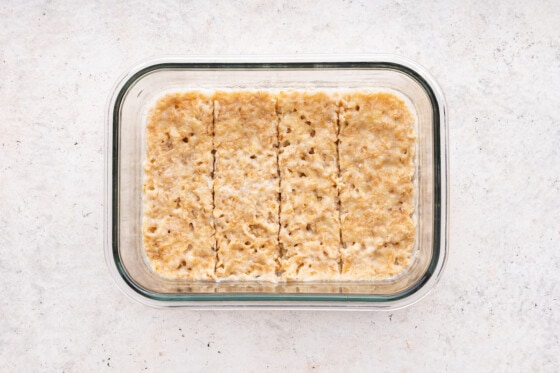 Cooked oatmeal fingers in a glass storage container.