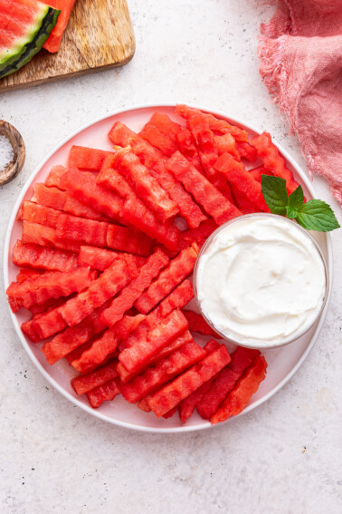 A plate of watermelon fries served with a yogurt dip.
