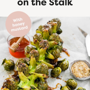 Roasted Brussels Sprouts on the Stalk with a bowl of honey and mustard beside it.