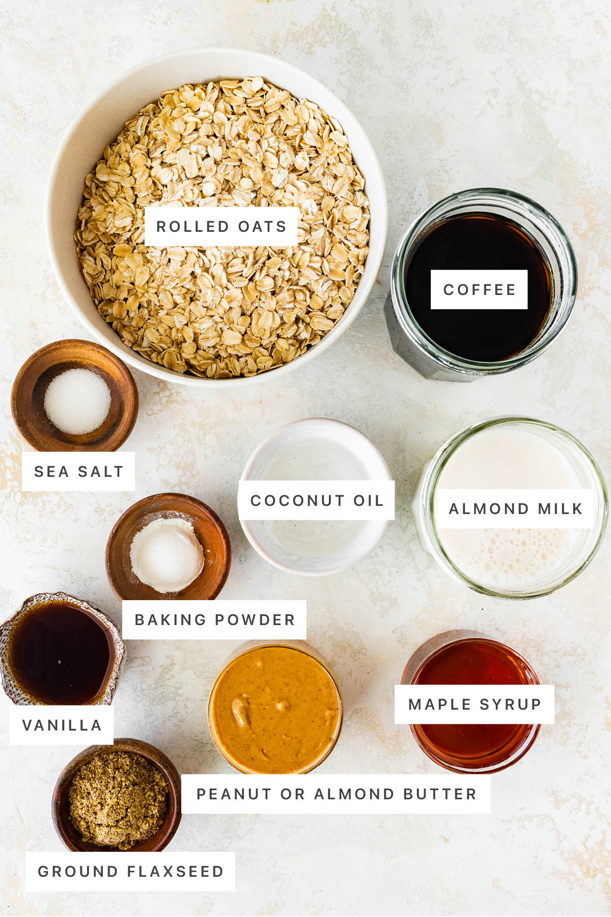 Ingredients measured out to make Coffee Baked Oatmeal: rolled oats, coffee, sea salt, coconut oil, almond milk, baking powder, vanilla, peanut or almond butter, maple syrup and ground flaxseed.