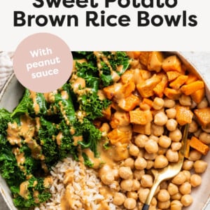 Bowl of brown rice, roasted sweet potato, chickpeas and kale, topped with peanut sauce.