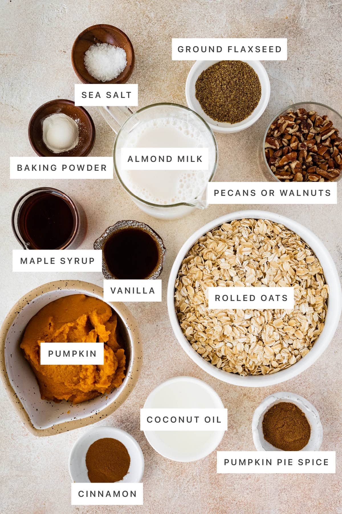Ingredients measured out to make Pumpkin Baked Oatmeal: sea salt, ground flaxseed, baking powder, almond milk, pecans, maple syrup, vanilla, rolled oats, pumpkin, coconut oil, cinnamon and pumpkin pie spice.