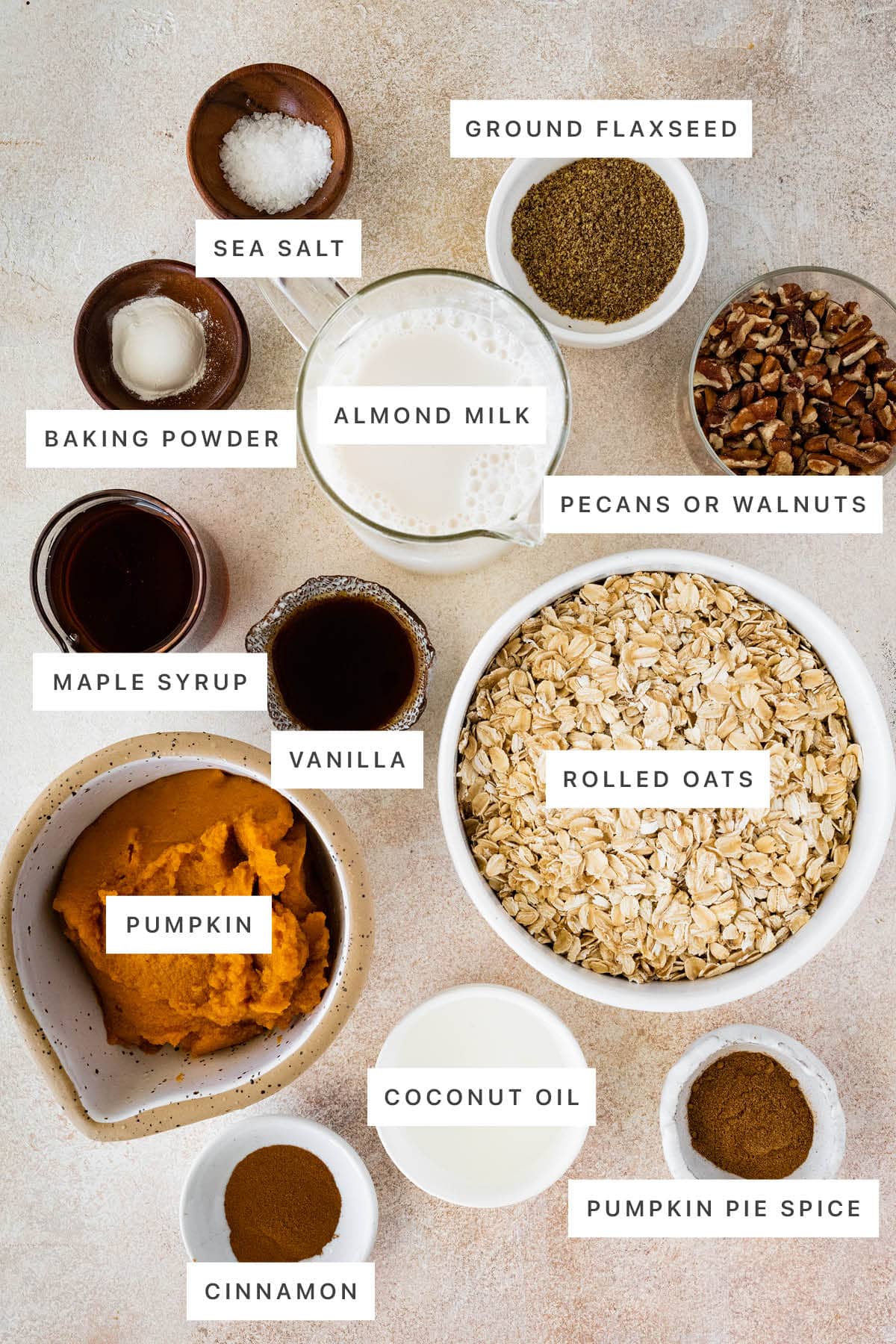 Ingredients measured out to make Pumpkin Baked Oatmeal: sea salt, ground flaxseed, baking powder, almond milk, pecans, maple syrup, vanilla, rolled oats, pumpkin, coconut oil, cinnamon and pumpkin pie spice.