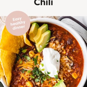 Bowl of Turkey Chili topped with cheese, sour cream, avocado, cilantro and chips.