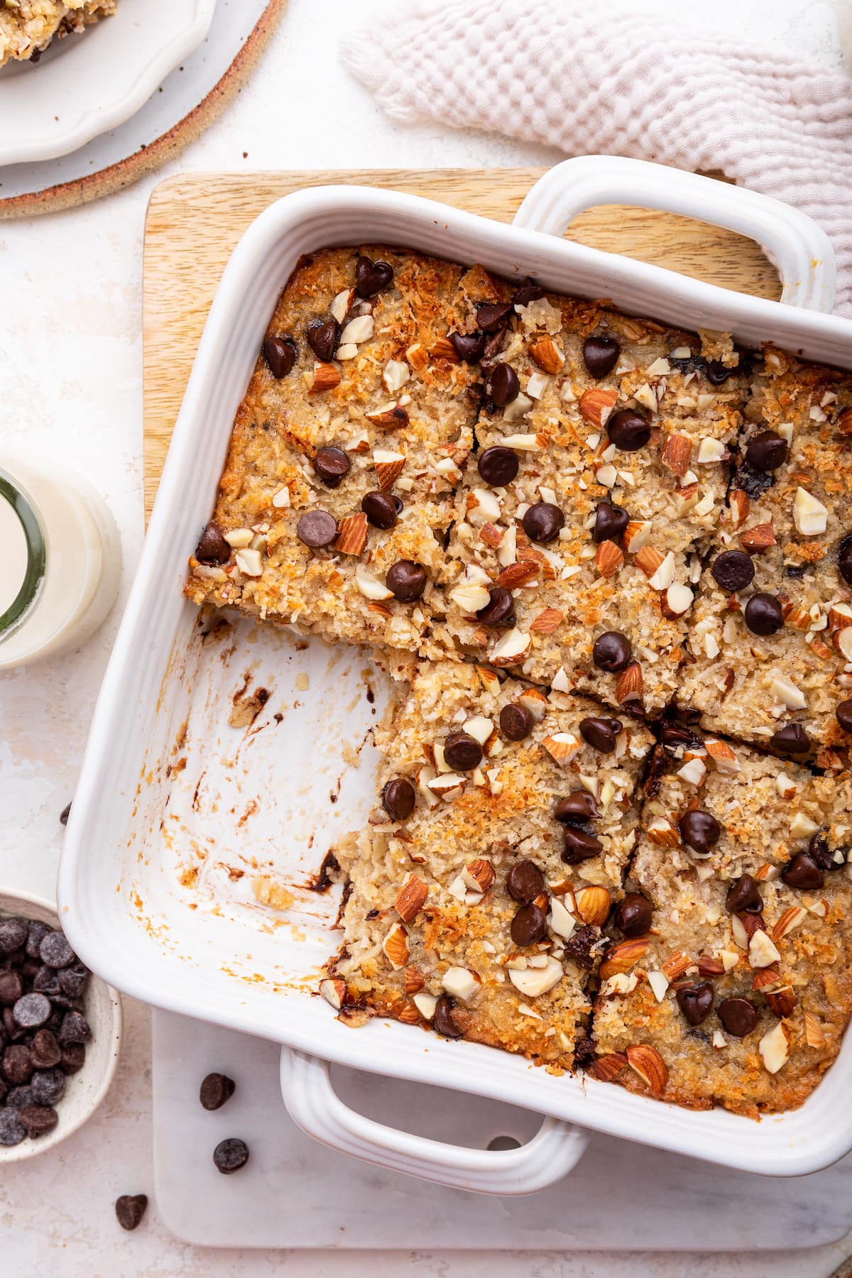 Almond joy baked oatmeal in a square baking dish with one piece missing.