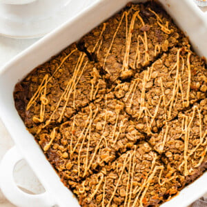 Coffee baked oatmeal sliced in a square baking dish and topped with a drizzle of nut butter.