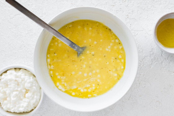 A small white bowl with eggs, cottage cheese, and a metal fork.