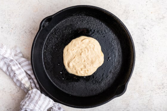 A cottage cheese pancake is cooked on a cast iron skillet.