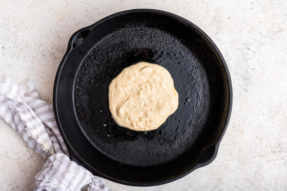 A cottage cheese pancake is cooked on a cast iron skillet.