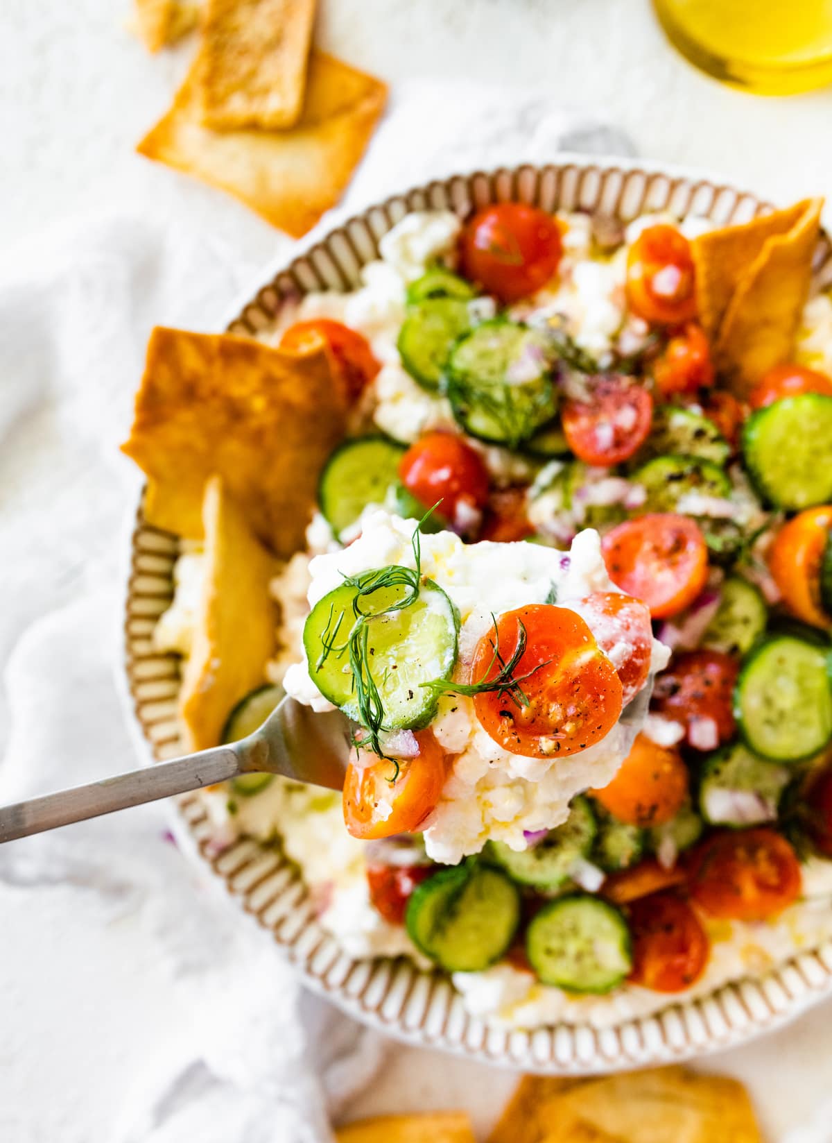 A fork holding a bite size portion of cottage cheese salad on it.