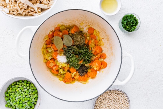 Sauted vegetables with herbs and spices in a large pot.