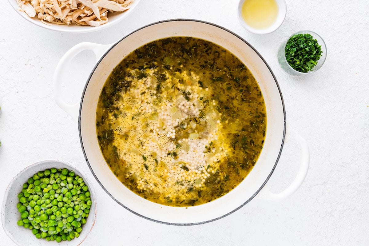 Broth added to a large pot with vegetables for turkey soup.