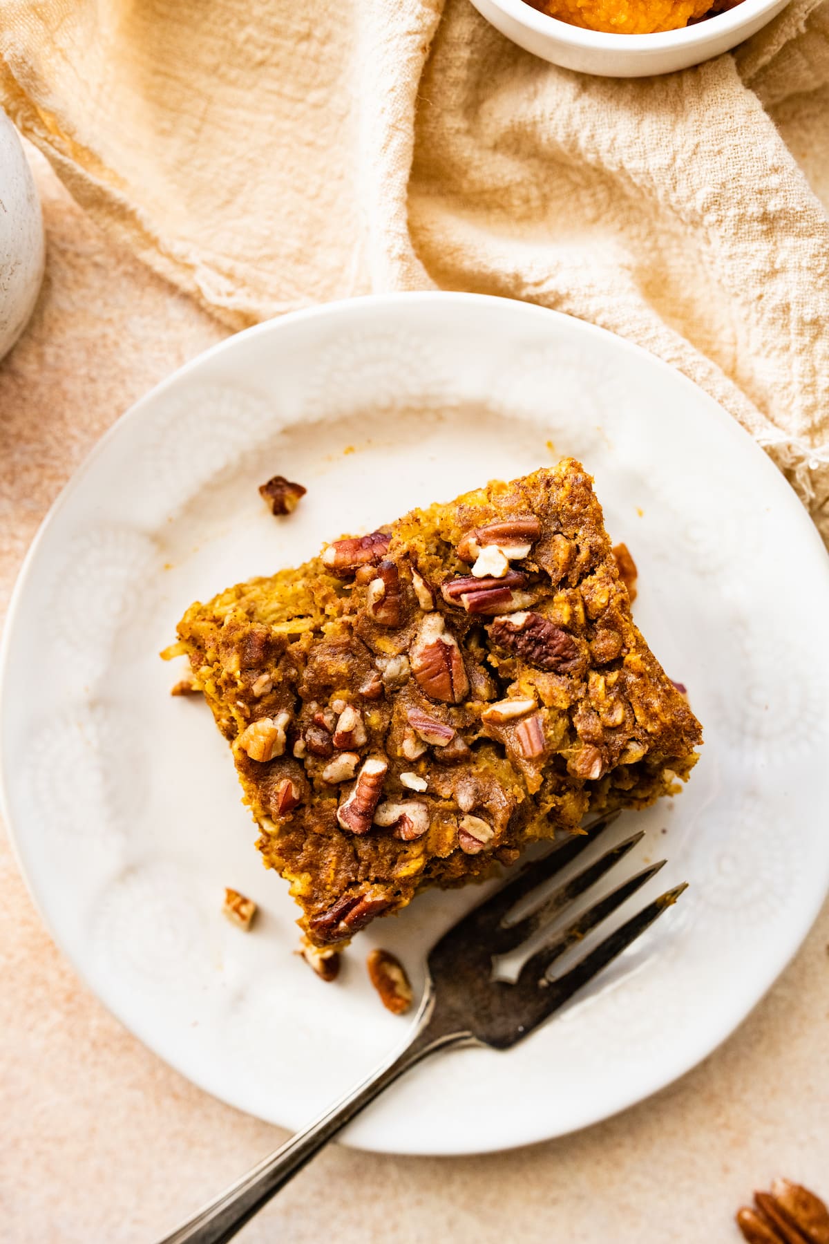 A serving of pumpkin baked oatmeal on a small white plate with a fork.