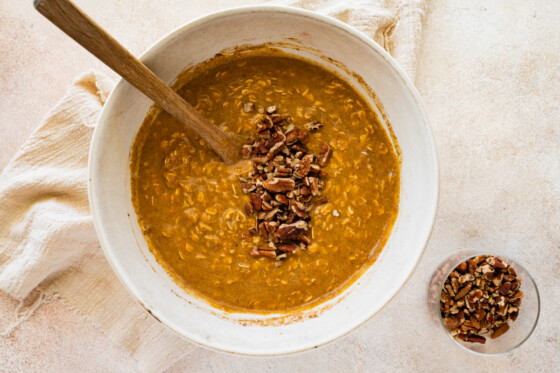 Wet and dry ingredients for the pumpkin baked oatmeal combined with pecans added in a large mixing bowl.