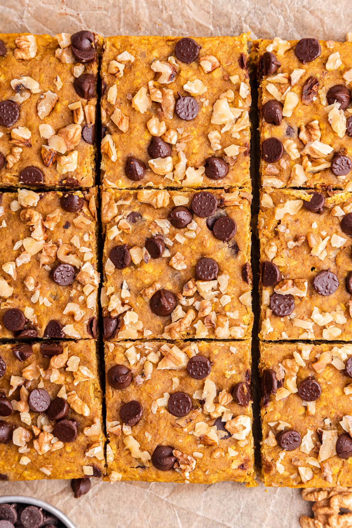 Nine pumpkin oatmeal bars close to each other on parchment paper.