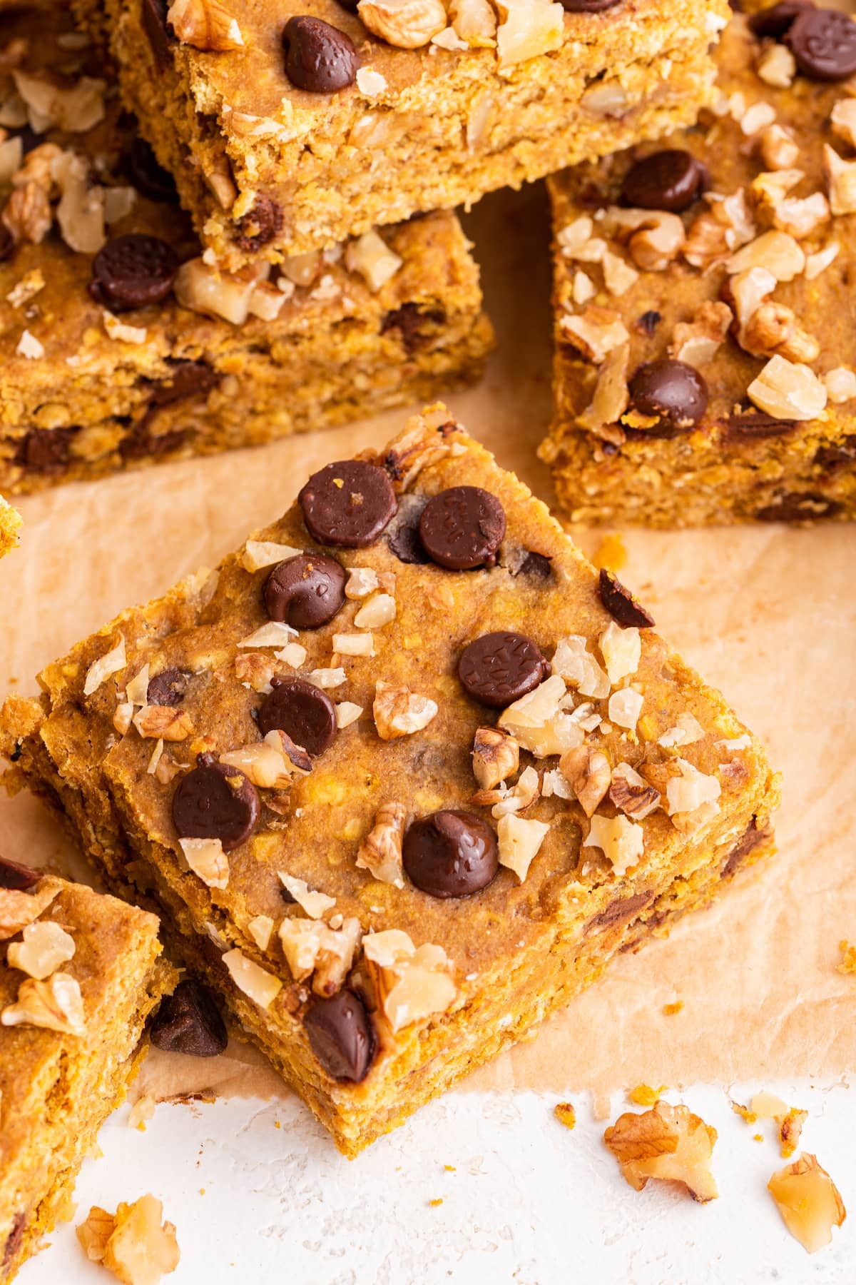 Pumpkin oatmeal bar with chocolate chips and crushed walnuts on parchment paper.