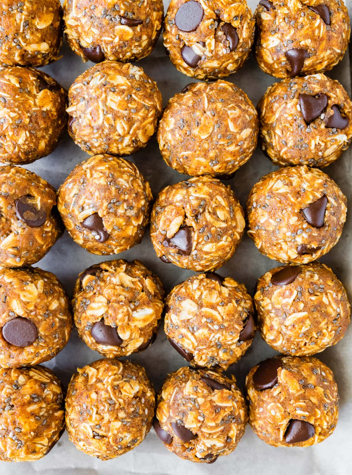 Pumpkin protein balls lined up near one another on parchment paper.