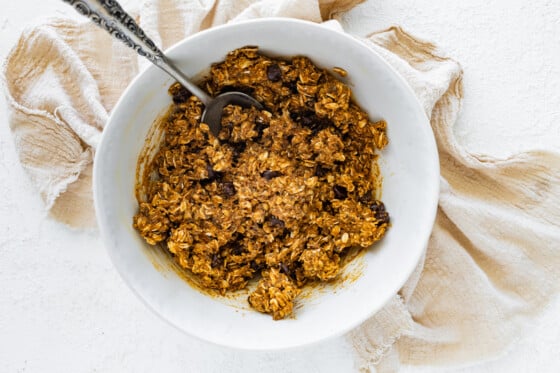 Mixture for the pumpkin protein balls in a large mixing bowl with a metal spoon.