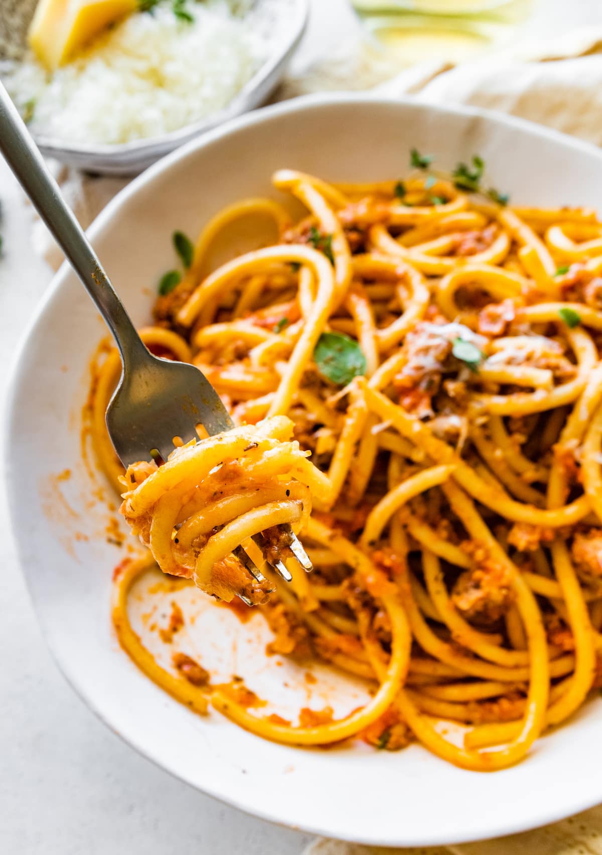 A fork with a bite size portion of spaghetti mixed with turkey bolognese.