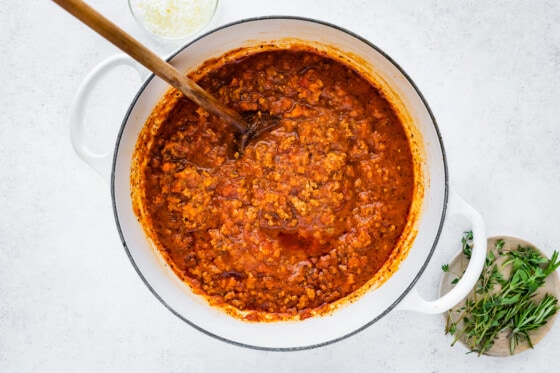 The complete turkey bolognese in a large dutch oven with a wooden spoon.