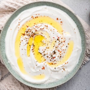 Whipped cottage cheese spread across a plate with a drizzle of olive oil and crushed red pepper.