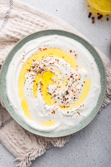Whipped cottage cheese spread across a plate with a drizzle of olive oil and crushed red pepper.