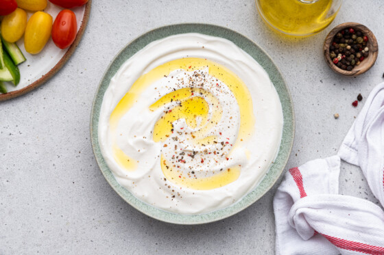 Whipped cottage cheese on a plate topped with a drizzle of olive oil and crushed red pepper.