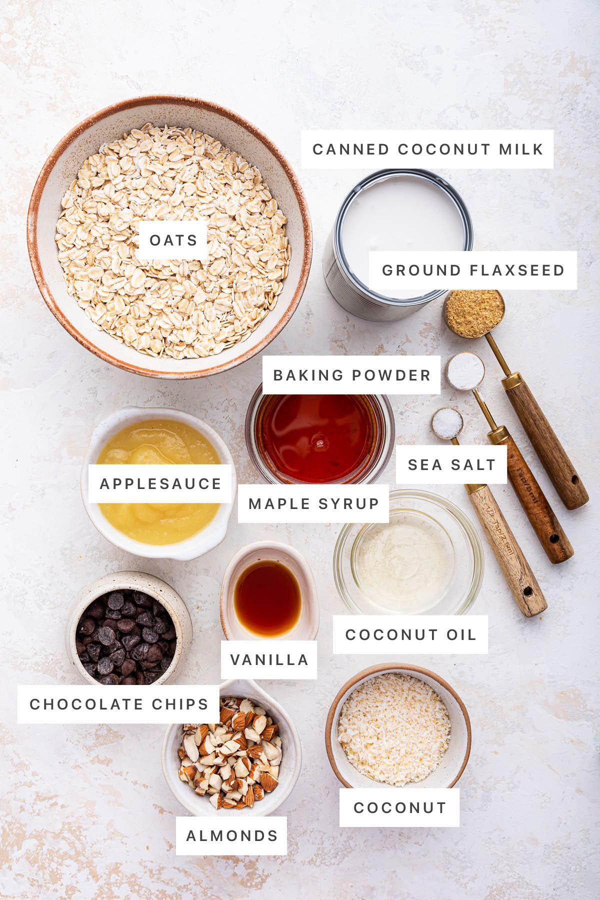 Ingredients measured out to make Almond Joy Baked Oatmeal: oats, canned coconut milk, ground flaxseed, baking powder, sea salt, maple syrup, applesauce, vanilla, coconut oil, chocolate chips, almonds and coconut.