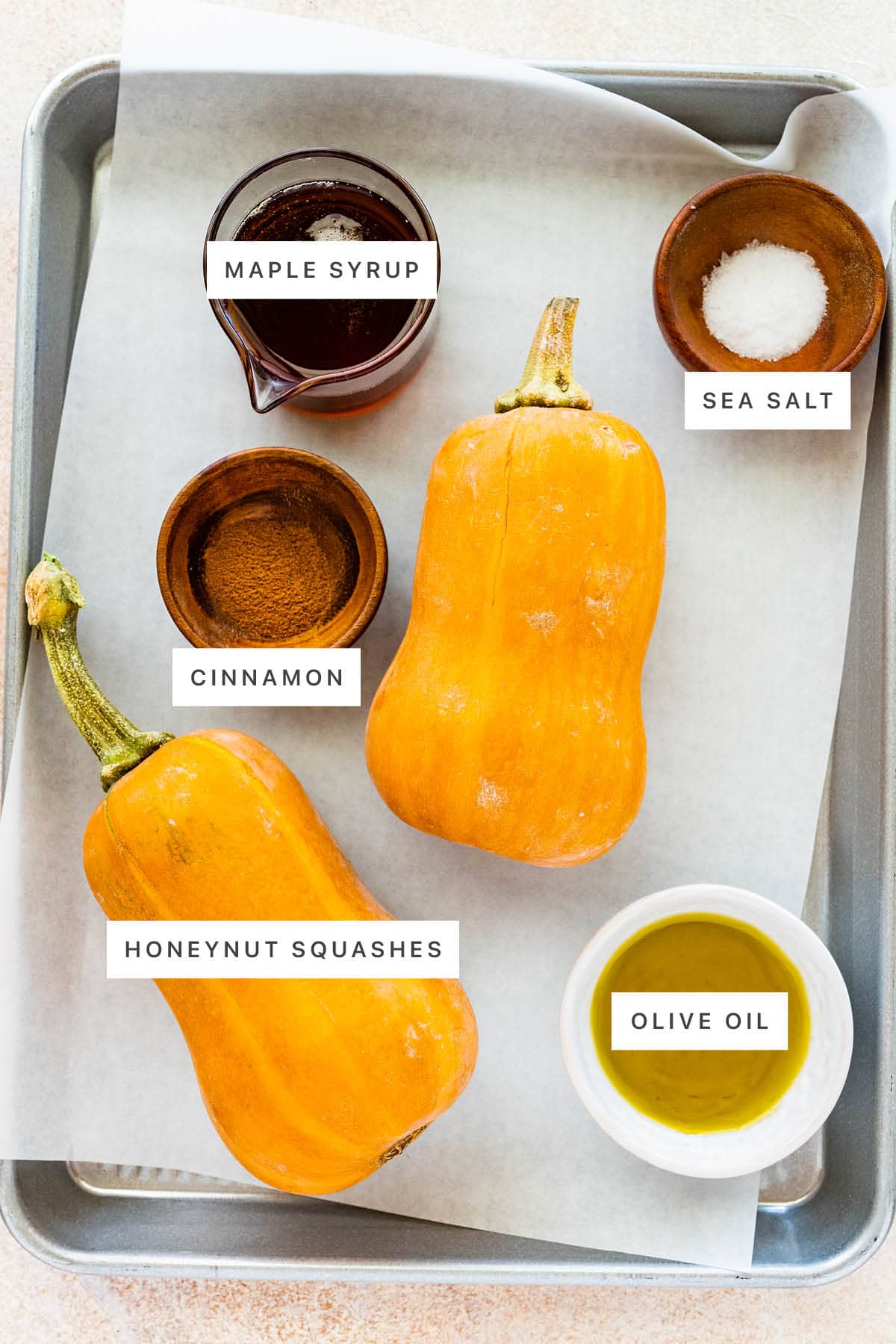 Ingredients measured out to make Roasted Honeynut Squash: maple syrup, sea salt, cinnamon, honeynut squashes and olive oil.