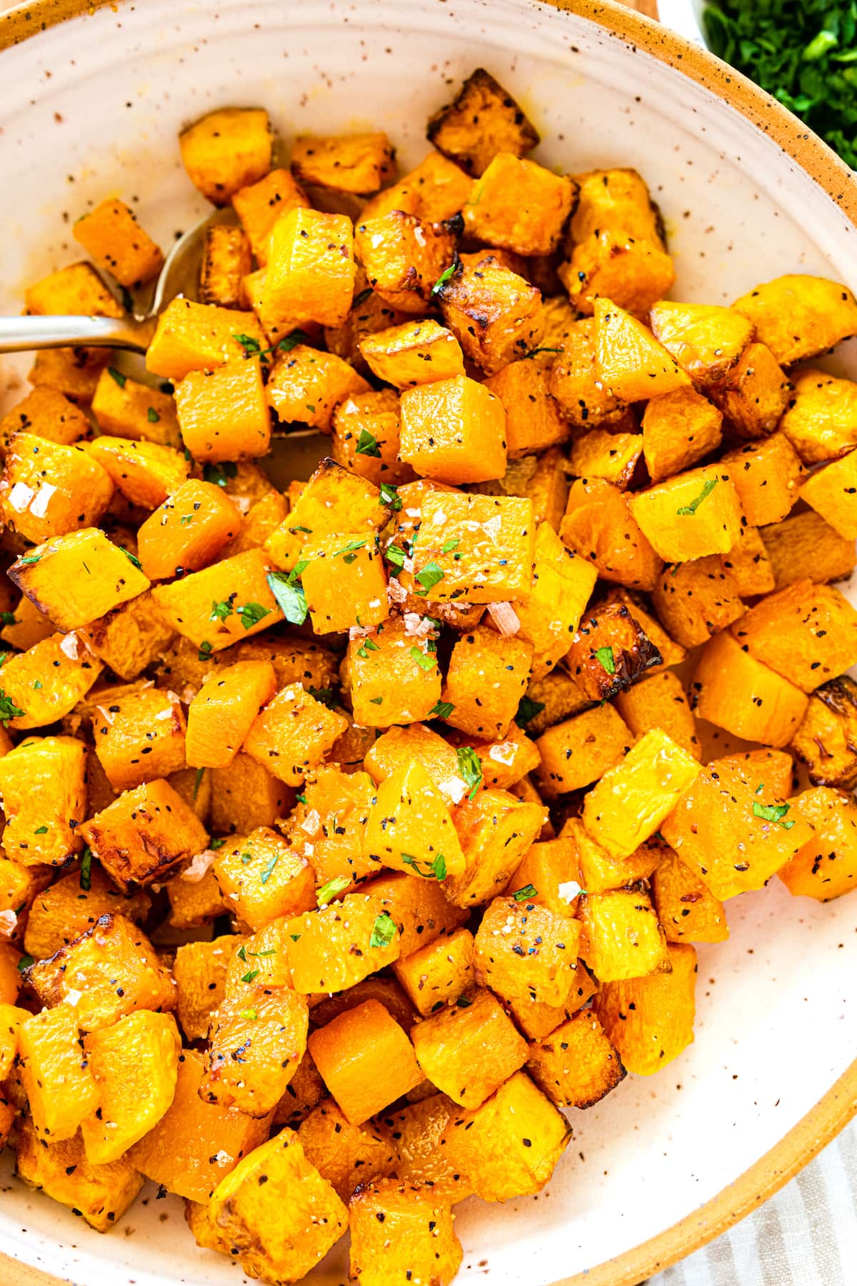 Seasoned and cubed butternut squash on a plate.