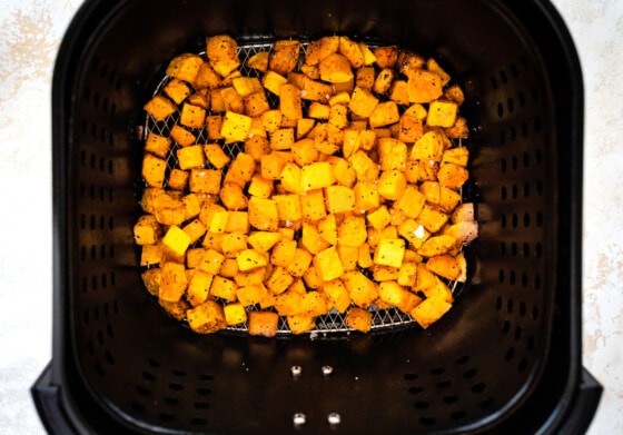 Seasoned and cubed butternut squash in an air fryer.