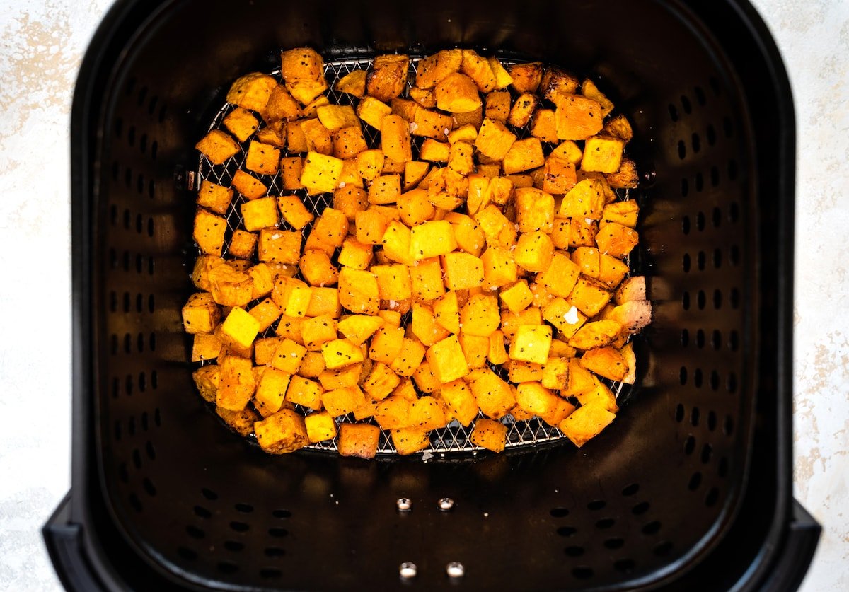 Seasoned and cubed butternut squash in an air fryer.