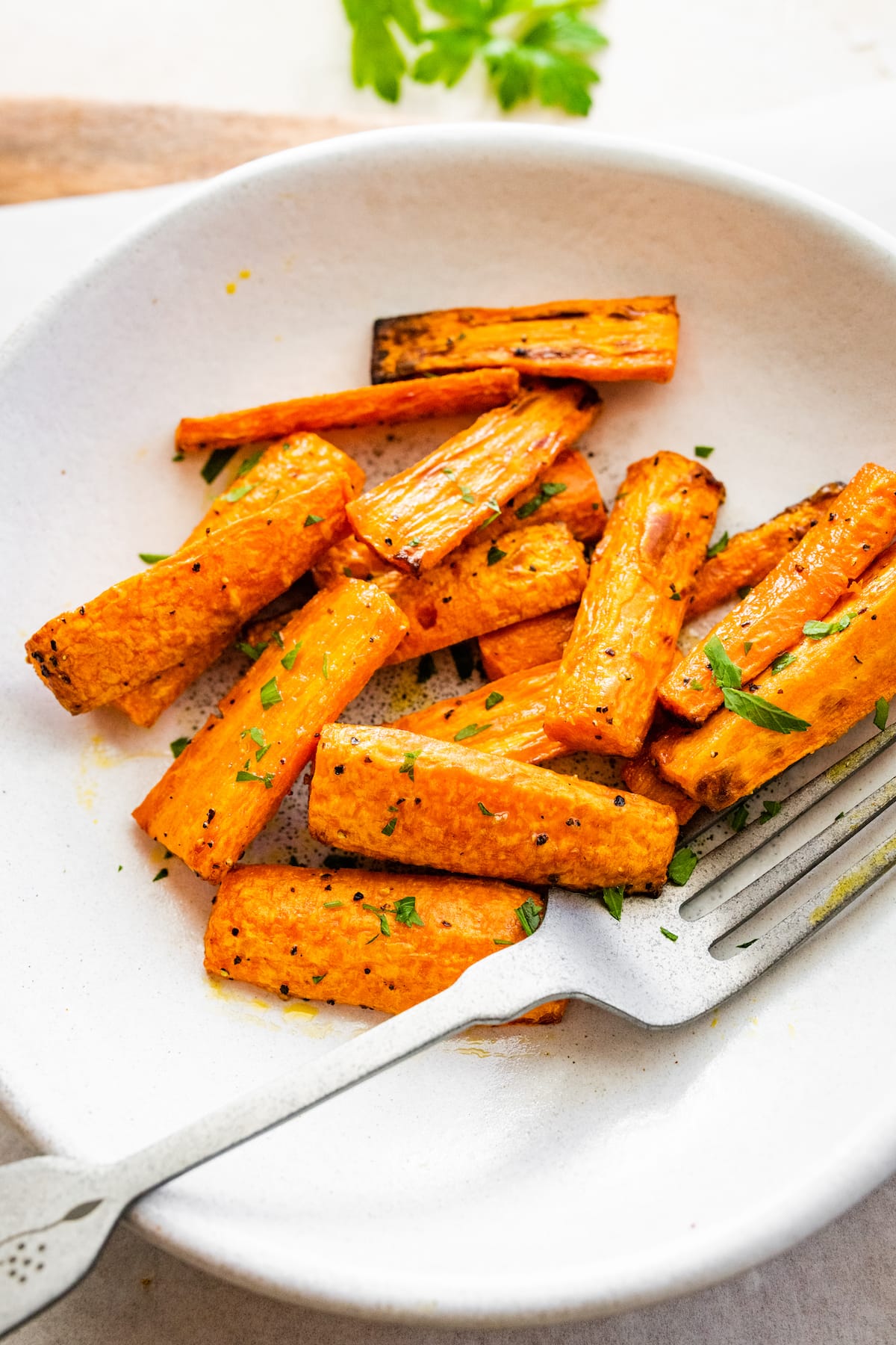 Air fried carrots cut into matchsticks on a plate and garnished with fresh herbs.