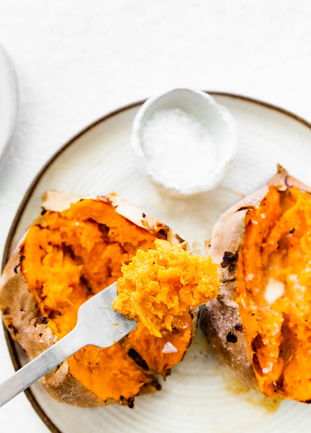 A fork with a small portion of sweet potato that has been air fried.