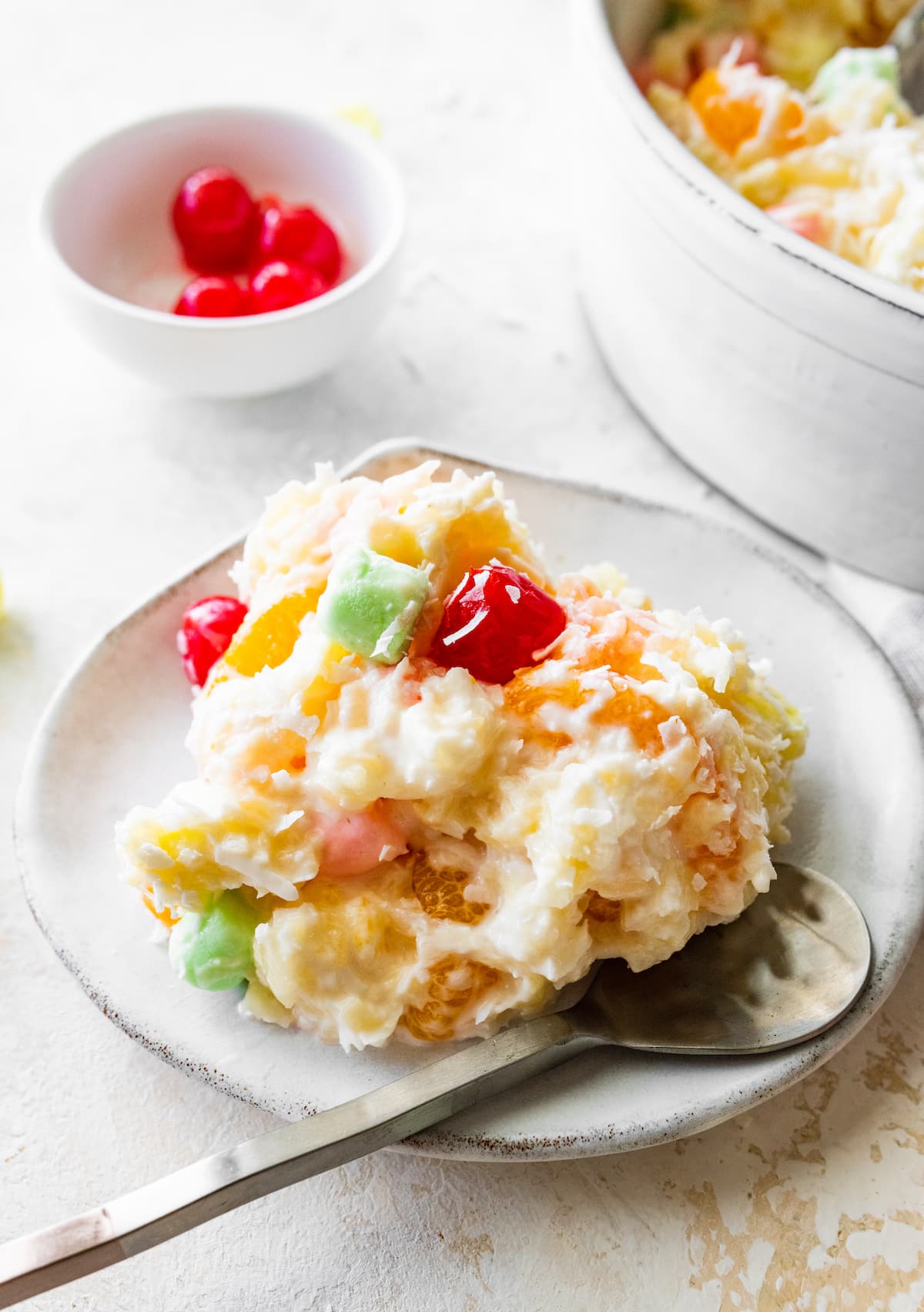 A serving of ambrosia salad on a small plate with a metal spoon.