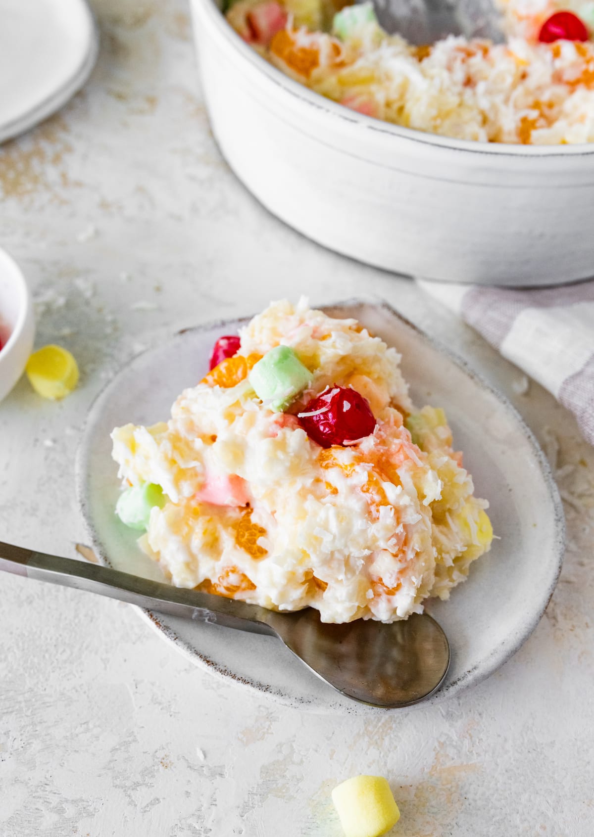 A serving of ambrosia salad on a small plate with a metal spoon.