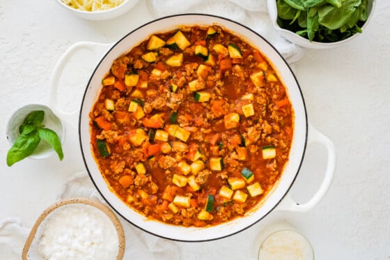 Cooked ground turkey with vegetables in a tomato-based sauce, which is in a large sauce pan.