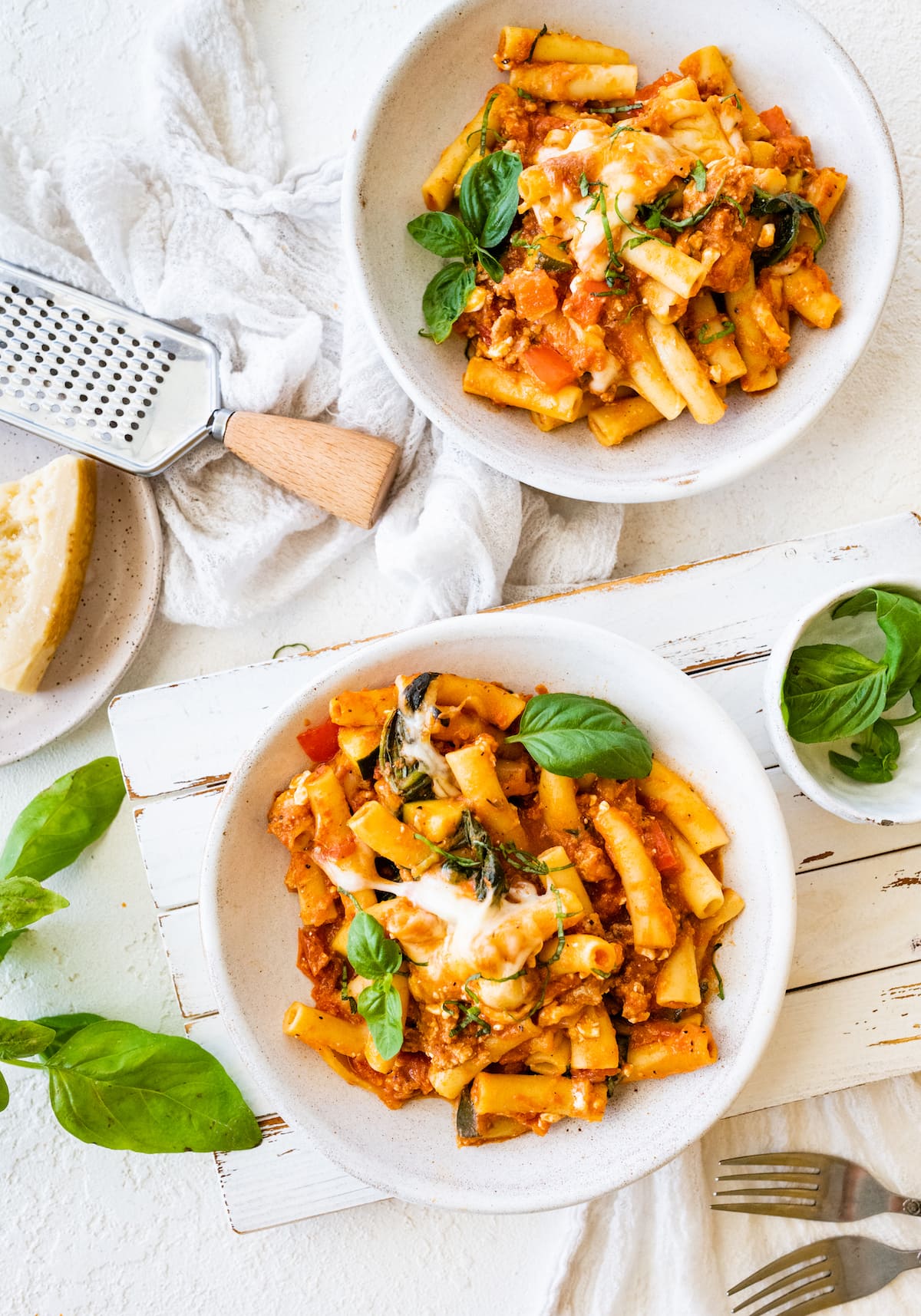 Two small white plates with servings of baked ziti.