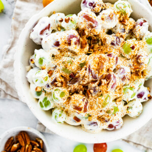 Creamy grape salad topped with sugar and crushed pecans in a large bowl.